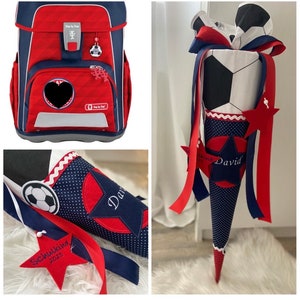Könnte beinhalten: Roter und blauer Schulranzen mit Fußball-Motiv. Ein passender rot-blau-weißer Schultüte mit Fußball-Motiv und dem Namen "David" ist ebenfalls abgebildet. Die Schultüte hat einen roten Stern mit dem Text "Schulkind 2023" darauf.