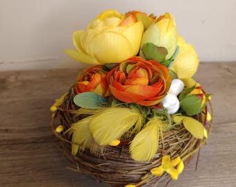 Composizione floreale con piccolo nido di fieno, tulipani, ranuncoli, uccellino