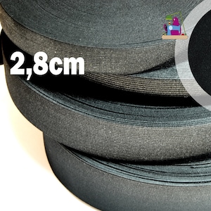 Könnte beinhalten: Eine Rolle dunkelgraues elastisches Band, ca. 2,8 cm breit, wird gezeigt. Ein Maßband wird verwendet, um die Breite des Bandes zu zeigen. Das Band ist eng aufgerollt, mit dem Text "2,8cm" in Weiß.