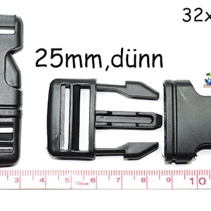 Könnte beinhalten: Schwarze Kunststoffschnalle mit einer Breite von 25 mm, beschriftet mit "25mm, dünn" und "32x60x8". Die Schnalle wird neben einem Lineal zur Größenreferenz gezeigt.