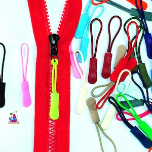 Peut inclure: Assortiment de tirettes de fermeture éclair de différentes formes et tailles, dans une variété de couleurs. Les tirettes de fermeture éclair sont faites d'un matériau souple et flexible, parfait pour ajouter une touche de couleur à n'importe quelle fermeture éclair.