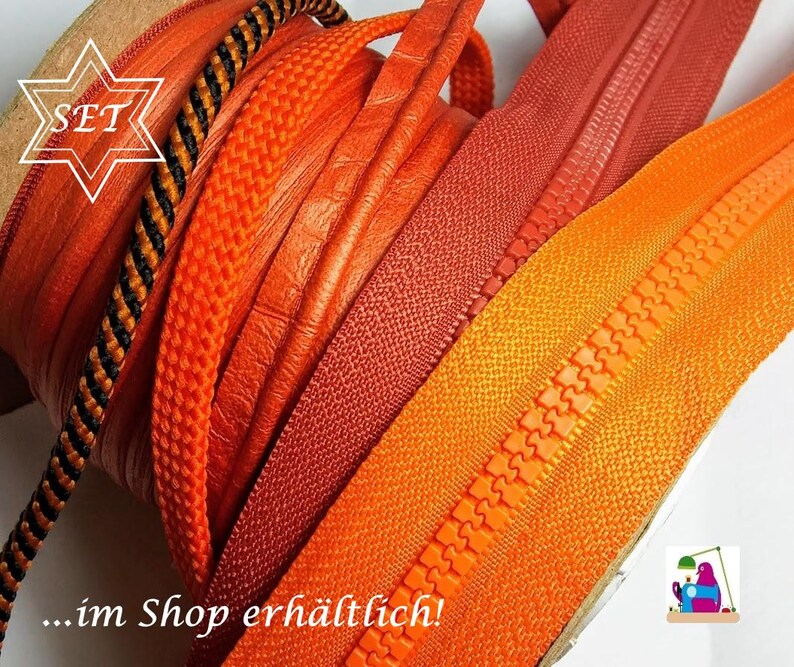 May include: A collection of sewing supplies featuring multiple rolls of orange and red zippers, a black and orange braided cord, and a textured orange trim. The image includes a white star-shaped graphic with the text SET and the text ...im Shop erh&auml;ltlich!
