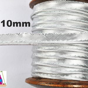 Könnte beinhalten: Eine Spule mit silberfarbener, 10 mm breiter Zierleiste. Die Zierleiste ist eng auf eine Holzspule gewickelt. Der Text "10mm" wird in Schwarz angezeigt und gibt die Breite der Zierleiste an. Die Zierleiste hat eine gewebte Textur.