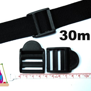 Könnte beinhalten: Ein schwarzes Nylongurtband mit einer Kunststoff-Leiterschnalle und zwei weiteren schwarzen Kunststoffschnallen. Der Text 30mm ist in Schwarz aufgedruckt. Ein weißes Maßband zeigt, dass die Schnallen etwa 30mm breit sind.