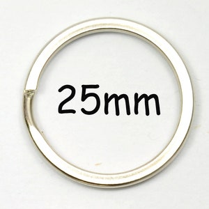 Könnte beinhalten: Ein silberfarbener Schlüsselring mit einem Durchmesser von 25 mm. Der kreisförmige Ring hat eine kleine Öffnung zum Befestigen von Schlüsseln oder anderen Gegenständen. Der Text "25mm" ist schwarz gedruckt.
