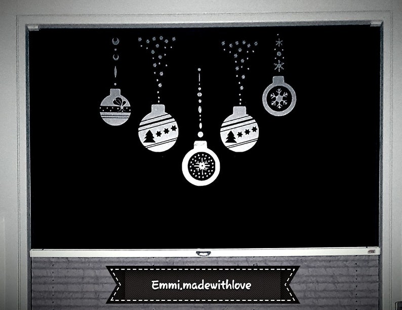 Puede incluir: Una superficie negra decorada con adornos navide&ntilde;os blancos. Los adornos incluyen copos de nieve, estrellas y un dise&ntilde;o de &aacute;rbol de Navidad. El texto "Emmi.madewithlove" se muestra en una pancarta en la parte inferior.