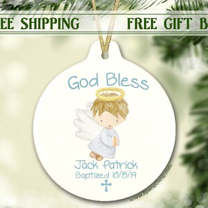 May include: White ceramic ornament with a blue and yellow angel illustration. The ornament says "God Bless" and "Jack Patrick Baptized 10/15/19".
