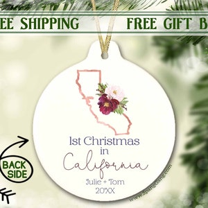 May include: White ceramic ornament with a rose gold outline of the state of California and a floral design. The ornament says "1st Christmas in California" and "Julie + Tom 20XX".