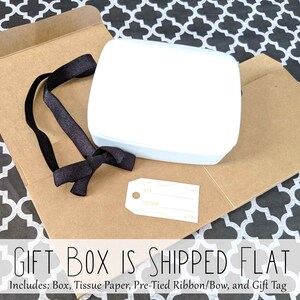 May include: A white gift box with a black ribbon and a gift tag that says "TO FROM". The box is shipped flat and includes tissue paper, a pre-tied ribbon, and a gift tag.