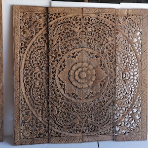 Puede incluir: Un conjunto de cinco paneles de pared de madera tallados intrincadamente con diseños florales. Los paneles están hechos de madera marrón claro y tienen un acabado natural. Los paneles están dispuestos en forma rectangular, con el panel más grande en el centro y los paneles más pequeños a cada lado.