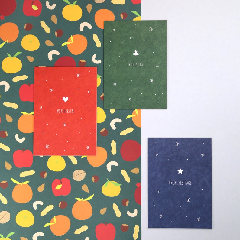 May include: Three Christmas cards with different designs. The first card is red with white snowflakes and the text "Von Herzen". The second card is green with white snowflakes and the text "Frohes Fest". The third card is blue with white stars and the text "Frohe Festtage".