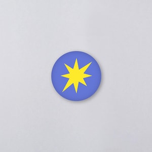 Könnte beinhalten: Ein runder, blauer Button mit einem gelben Sternenmuster. Der Stern hat acht Zacken und ist mittig auf dem Button platziert. Der Button befindet sich vor einem schlichten, hellgrauen Hintergrund.