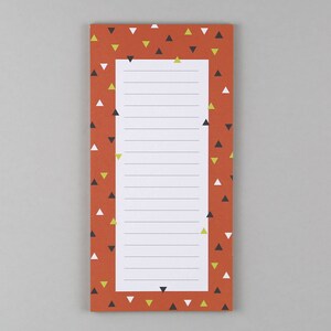 Könnte beinhalten: Ein roter Notizblock mit einem Muster aus weißen, schwarzen und gelben Dreiecken. Der Notizblock hat liniertes Papier und ist perfekt zum Notieren von Notizen oder zum Erstellen von Listen.