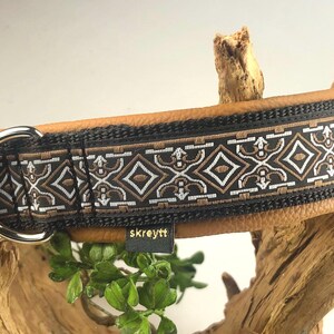 Könnte beinhalten: Ein braunes Lederhundekragen mit einem schwarzen und weißen Muster. Das Halsband hat eine silberne Schnalle und einen D-Ring. Der Markenname "skreytt" ist auf dem Halsband sichtbar.