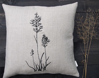 May include: A beige linen pillow with black embroidered grass designs.