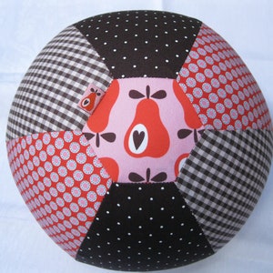 Könnte beinhalten: Ein Patchwork-Ball mit einem pinkfarbenen, roten und braunen Birnenmuster. Der Ball besteht aus verschiedenen Stoffen mit Punkten, Karos und Blumenmustern.