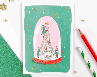 Carte de Voeux Tour Eiffel dans une boule à neige avec les lutins de Noël. Carte postale pour Noël et les fêtes de fin d'année. Noël à Paris