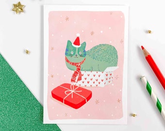Carte de Voeux, Chat de Noël assis dans un emballage de cadeau. Carte postale pour les fêtes de fin d'année