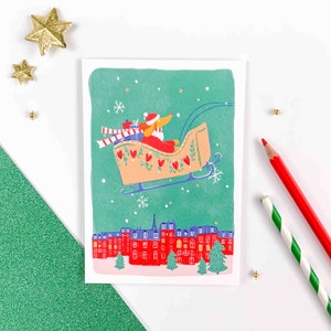Carte de Voeux Père Noël Chien dans un traineau volant au dessus de Paris et sa Tour Eiffel comme un sapin. Noël à Paris