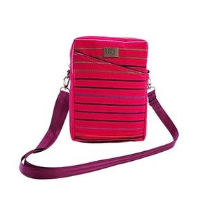 May include: A rectangular crossbody bag in a vibrant fuchsia color, adorned with horizontal stripes in various colors. The bag features a matching adjustable shoulder strap and a small, rectangular leather patch with a logo.