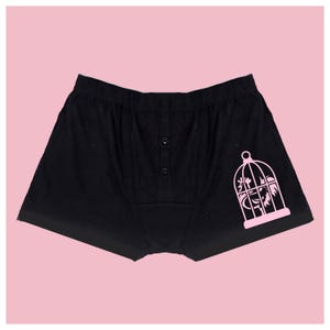 May include: Black boxer shorts with a pink bird in a cage graphic print.