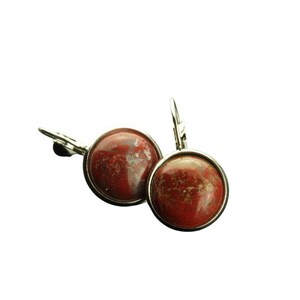 Könnte beinhalten: Ein Paar silberne Ohrringe mit roten Jaspis-Cabochons. Die Ohrringe haben ein schlichtes, elegantes Design.