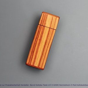 Könnte beinhalten: Ein rechteckiger USB-Stick mit einer natürlichen Holzmaserung und markanten vertikalen braunen und beigen Streifen. Das Gerät besteht aus einem Hauptgehäuse und einer abnehmbaren Kappe, beide aus Holz gefertigt, mit einer glatten Oberfläche.