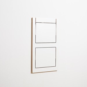 May include: A white rectangular wall art piece with two black outlined squares.