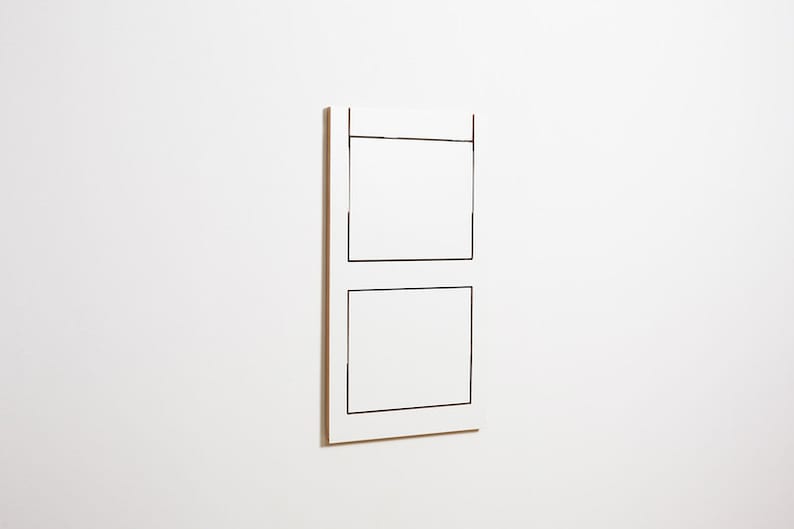 May include: A white rectangular wall art piece with two black outlined squares.