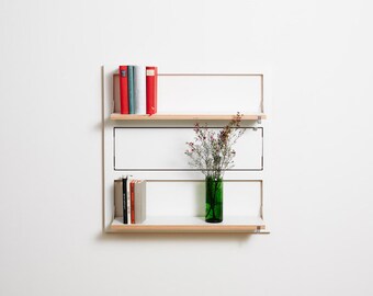 Puede incluir: Estantería blanca de pared con dos estantes. El estante superior tiene una pila de cinco libros, y el estante inferior tiene un jarrón con flores rosas y una pila de tres libros.