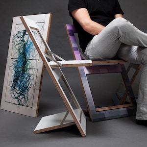 May include: Two folding chairs with colorful geometric patterns and a white folding chair with a blue and green abstract design. The chairs are made of wood and have a metal frame.