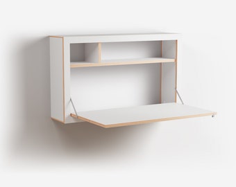 May include: White wall-mounted desk with a fold-down surface and shelves. The desk is made of wood and has a light wood trim.