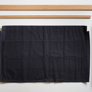 May include: A dark blue fabric wall organiser with five shelves and two wooden side rails. The side rails have holes for screws or nails to hang the organiser on a wall.