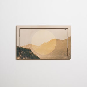 May include: A framed print of a mountain landscape with a large, yellow sun in the background.