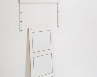 Può includere: Due tavoli pieghevoli a parete bianchi con cornice in legno. Il tavolo superiore è un pannello singolo, mentre il tavolo inferiore ha due pannelli.