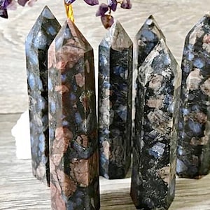 Könnte beinhalten: Sechs schwarze und blaue Edelstein-Spitzen mit einem gesprenkelten Muster. Die Spitzen sind in einer Reihe auf einer Holzoberfläche angeordnet.