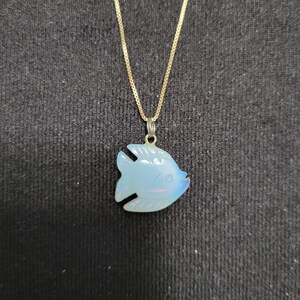 May include: A gold chain necklace with a blue iridescent fish pendant.