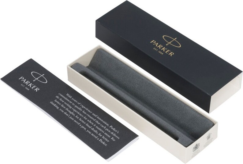 May include: A black and white box with the Parker logo and the text "EST. 1888". The box is open and the inside is lined with gray felt. The box is for a pen.