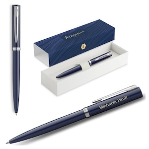 Könnte beinhalten: Ein marineblauer Waterman-Stift mit silbernen Akzenten, zusammen mit seiner Präsentationsbox. Die Box ist marineblau mit einem Wellenmuster und dem Waterman-Logo. Der Stift wird in verschiedenen Ansichten gezeigt.