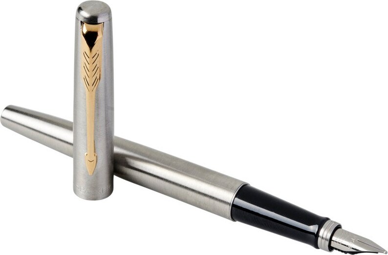 May include: A silver and black fountain pen with a gold-colored trim and a fine nib. The pen is capped and the cap is lying next to the pen.