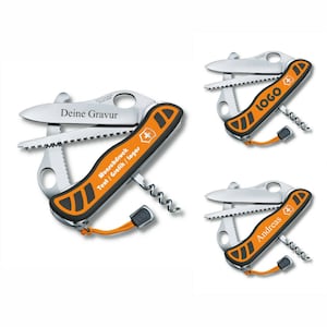 Puede incluir: Tres navajas de bolsillo multiherramienta con mangos naranja y negro. Las navajas tienen una variedad de herramientas, incluyendo una sierra, una cuchilla y un sacacorchos. Las navajas están personalizadas con el texto "Deine Gravur", "LOGO" y "Andreas".