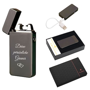 May include: A dark gray, rectangular lighter with the text "Deine persönliche Gravur" and two hearts. The lighter is open, revealing the ignition mechanism. A USB charging cable and a gift box are also shown.