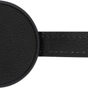 Puede incluir: Tap&oacute;n de botella de cuero negro con parte superior redonda y una correa cosida.