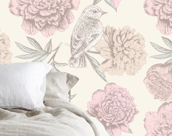 Op de afbeelding: Een beige en witte bloemenbehang met een delicaat vogelontwerp. Het behang heeft roze en perzikkleurige pioenen met groene bladeren. Het behang wordt getoond in een slaapkamersetting met een wit kussen en een beige dekbed.