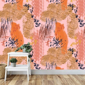 May include: Abstract wallpaper with a pink background and orange, brown, and blue abstract shapes. The wallpaper is shown on a wall with a white shelf and two potted plants.