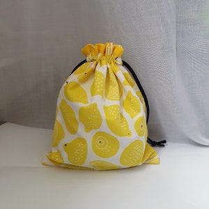 Könnte beinhalten: Eine gelbe Kordeltasche mit Zitronenprint. Die Tasche hat eine schwarze Kordel.