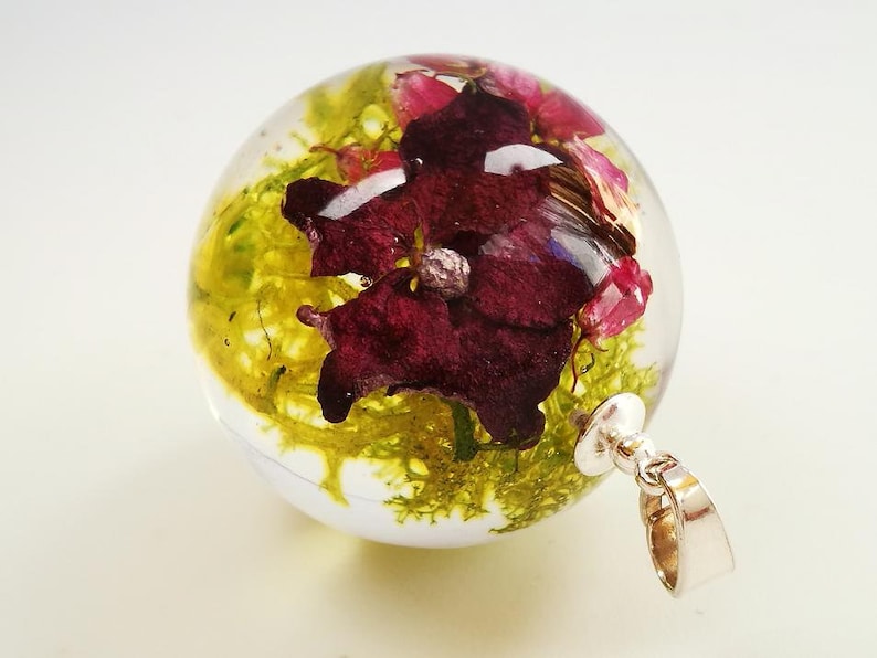 Growths and pink hydrangea necklace in sphere from resin composition in resin