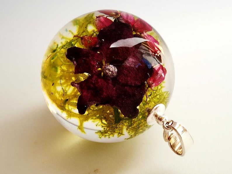 Growths and pink hydrangea necklace in sphere from resin composition in resin