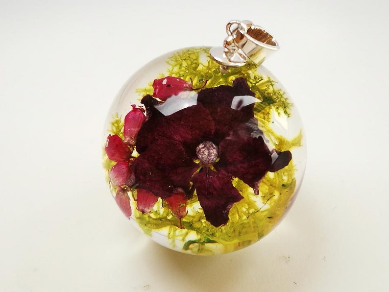 Growths and pink hydrangea necklace in sphere from resin composition in resin