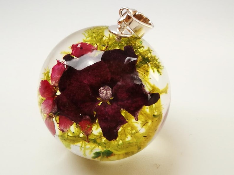 Growths and pink hydrangea necklace in sphere from resin composition in resin